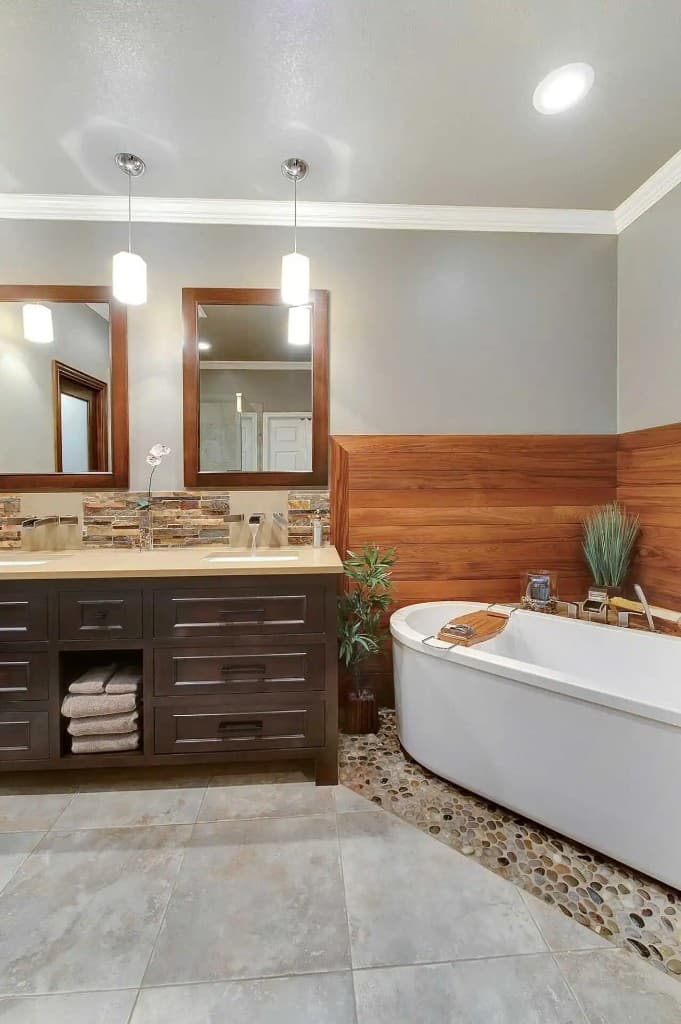 Remodeled bathroom with double vanity, stone backsplash, and freestanding tub